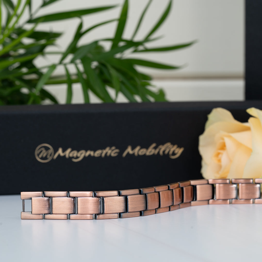Alexander's Copper Magnetic Bracelet laid flat in front of a Magnetic Mobility gift box, emphasising the precise craftsmanship and smooth copper links.