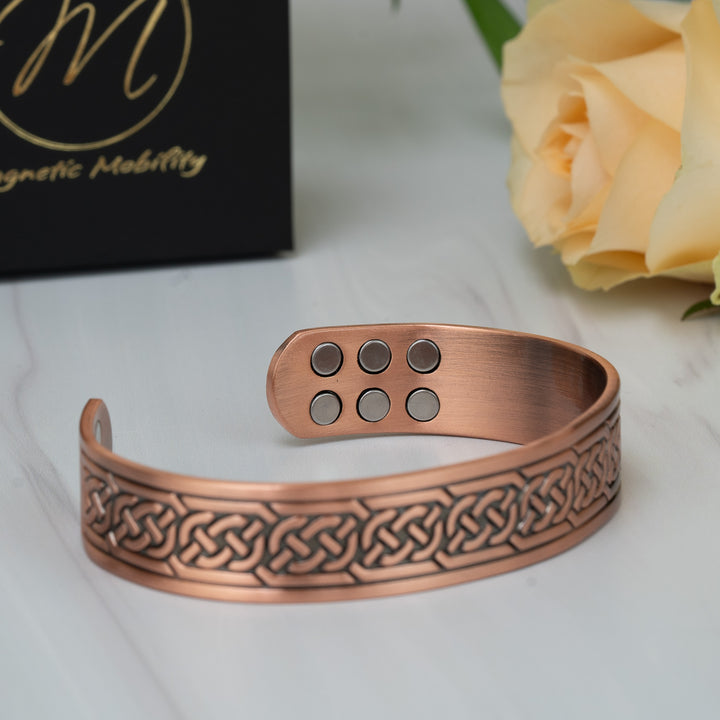 Angled view of the Burdock Copper Bracelet highlighting the textured Celtic knot pattern and smooth copper finish.