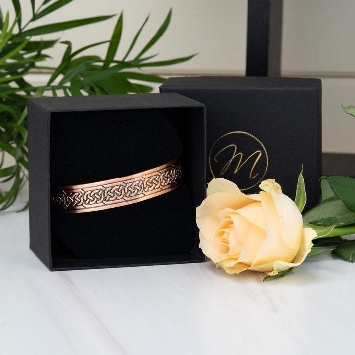 The Burdock Copper Bracelet elegantly displayed in its luxurious Magnetic Mobility gift box, with a soft velvet interior and a yellow rose accent.