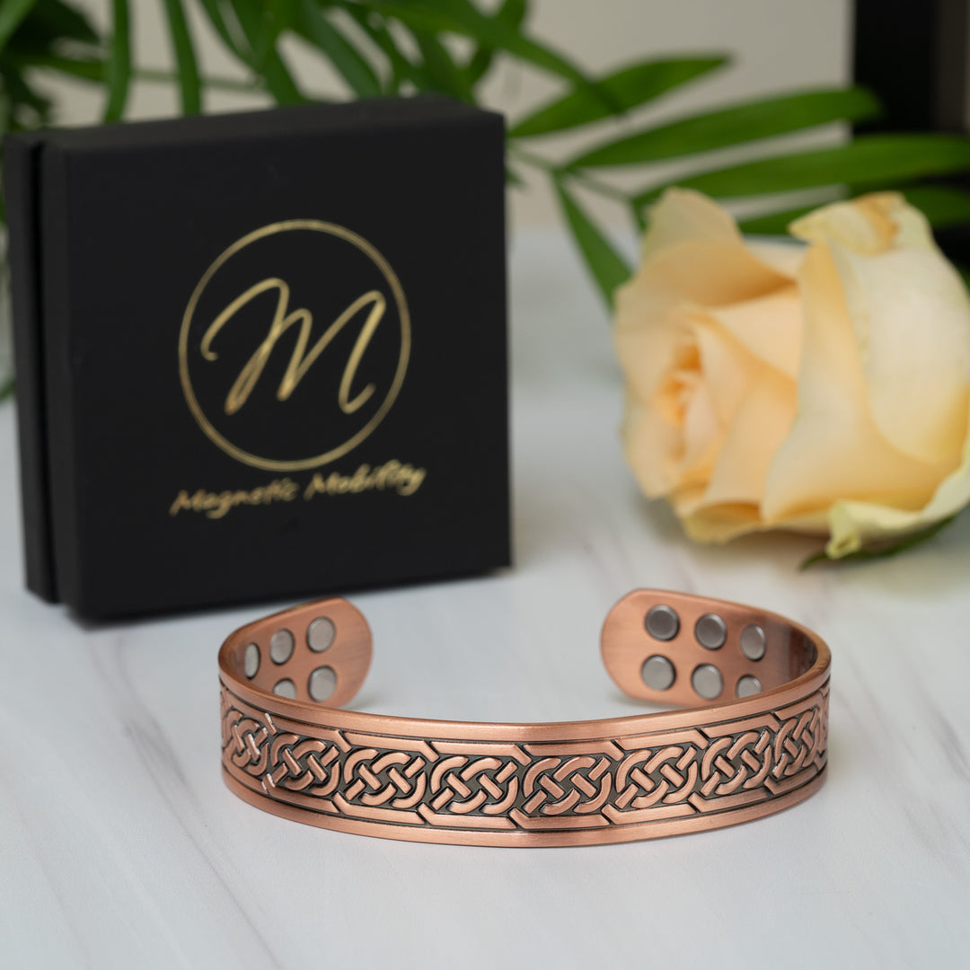 Top view of the Burdock Copper Bracelet showcasing its open bangle design with Celtic knots and embedded magnets visible on the inner side.