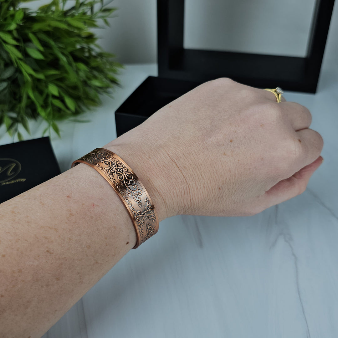 The Campion Copper Bracelet worn on a wrist, highlighting its adjustable open-backed design and the elegant pattern that complements any style.