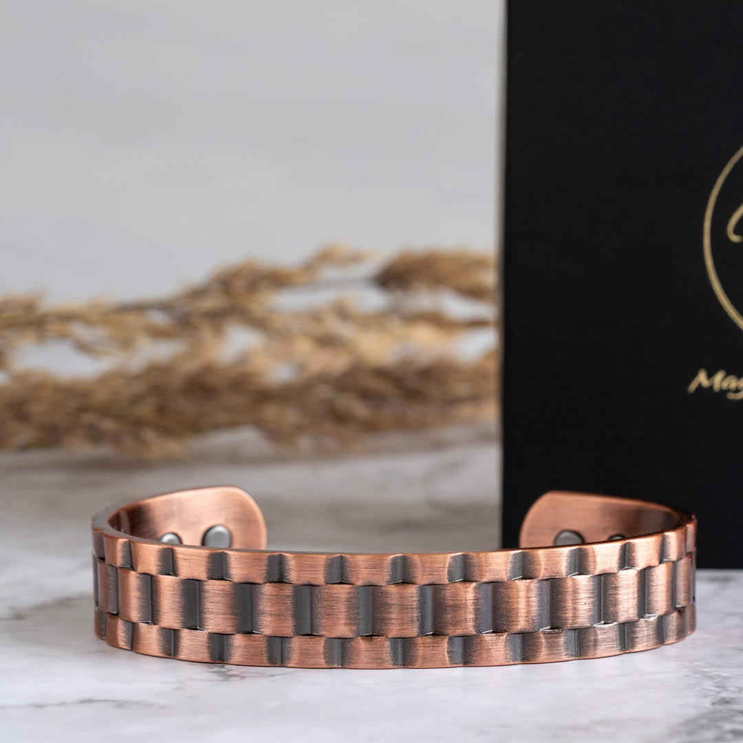 Close-up view of Columbine Copper Bracelet with intricate alternating band design, displayed against a marble background with Magnetic Mobility packaging