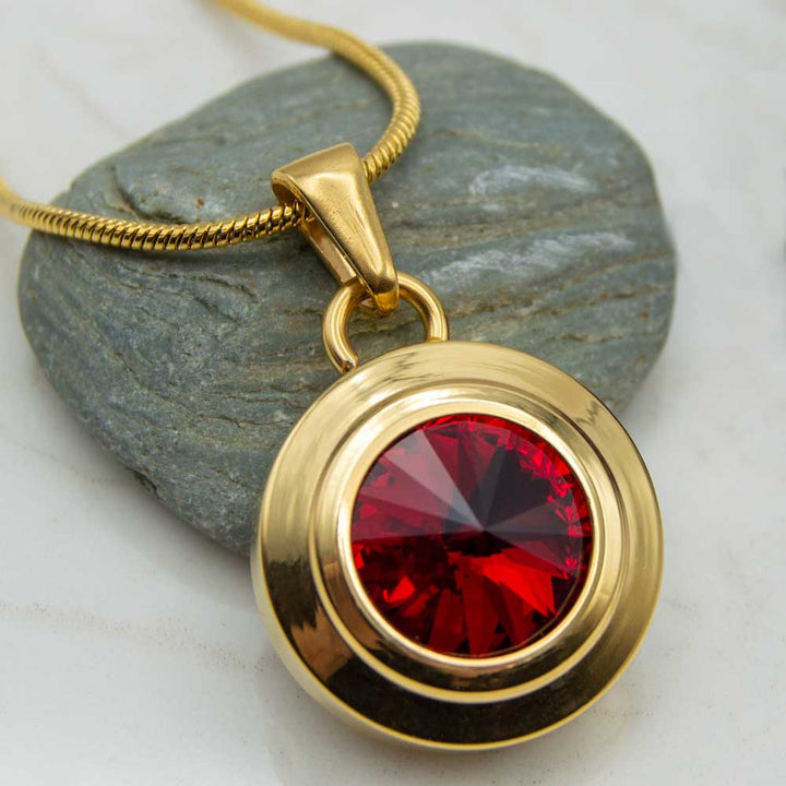 Front view of the Angelica sun gold palted stainless steel magnetic necklace for people with arthritis. The Necklace has a red Swarovski stone .