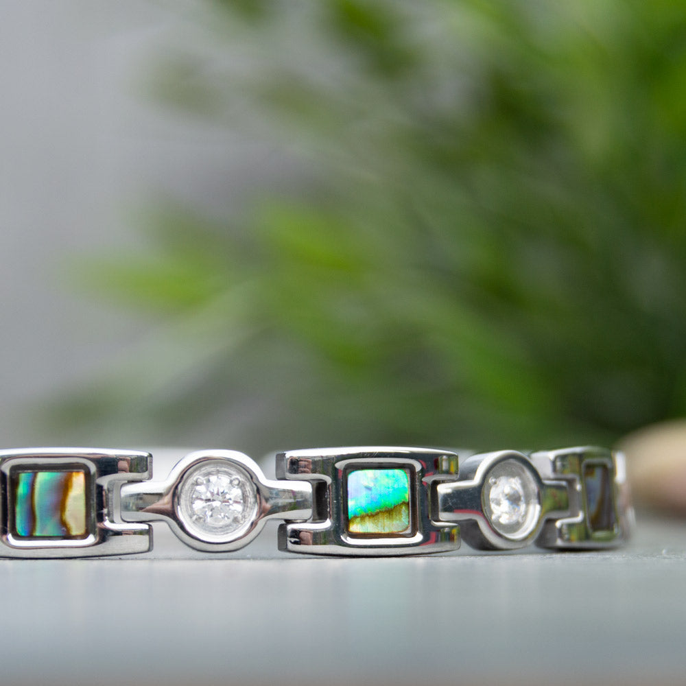 Close up view of Avens Moon Silver Magnetic Bracelet showing the irredessant desings in blue and green. White Crystals.