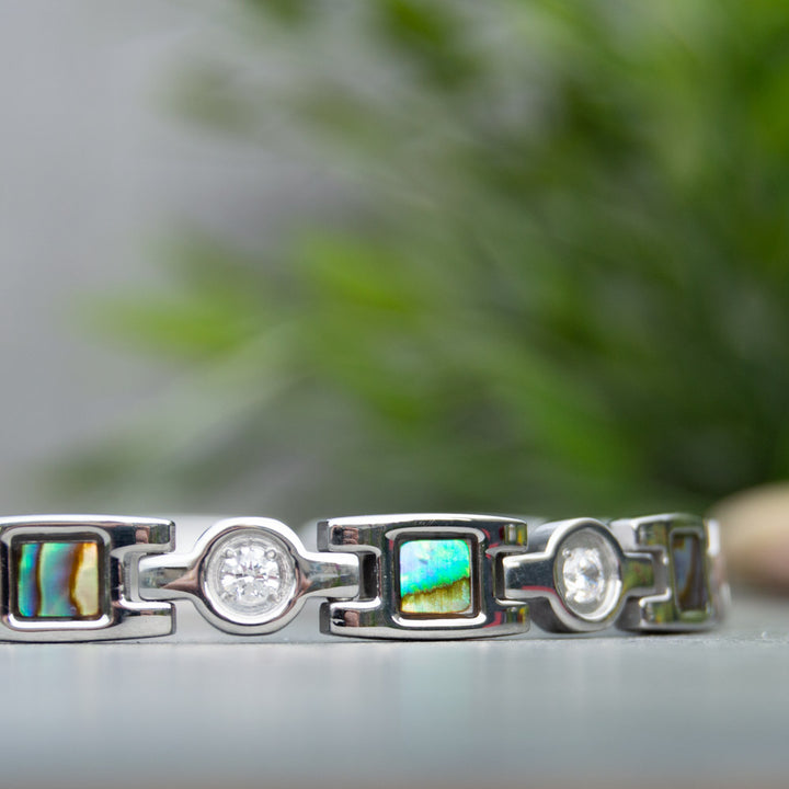 Close up view of Avens Moon Silver Magnetic Bracelet showing the irredessant desings in blue and green. White Crystals.