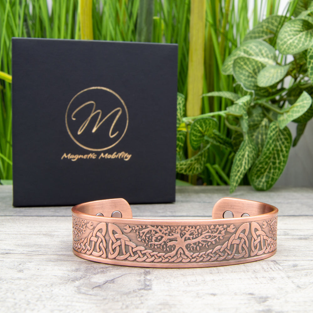 Tree of life design Copper Bracelet. Detailed image of the thick Buckthorn Copper Bracelet with strong neodymium magnets, a potential aid for arthritis and pain relief, complemented by a luxury black eco-friendly gift box.