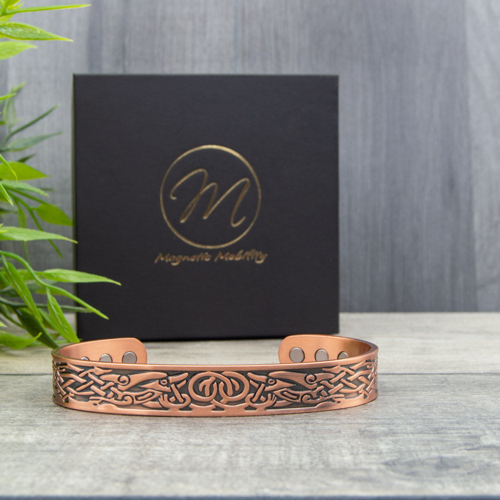 Irish design copper bracelet with magnets for arthrits relief. THe celtic design bracelet is shown in front of a Black gift box with Magnetic Mobility's logo