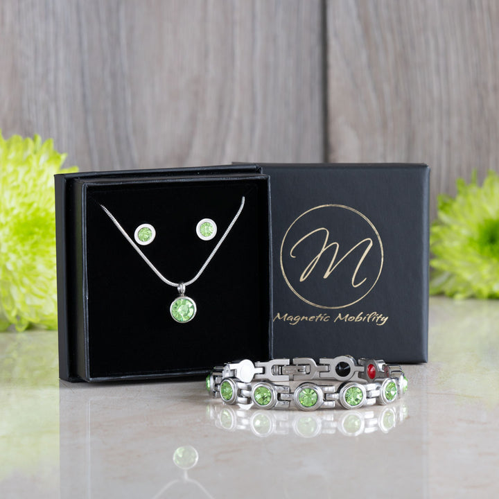 Comprehensive view of the August Birthstone gift set including a magnetic necklace, earrings, and bracelet adorned with Swarovski Peridot crystals, displayed elegantly in black packaging with green floral accents. Perfect for August birthday gifts, combining style and wellness.