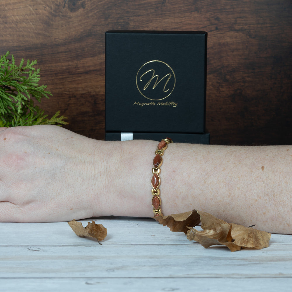 Magnetic Bracelet on a wrist with a wooden background and a box labeled 'Magnetic Jewelry' in the background.