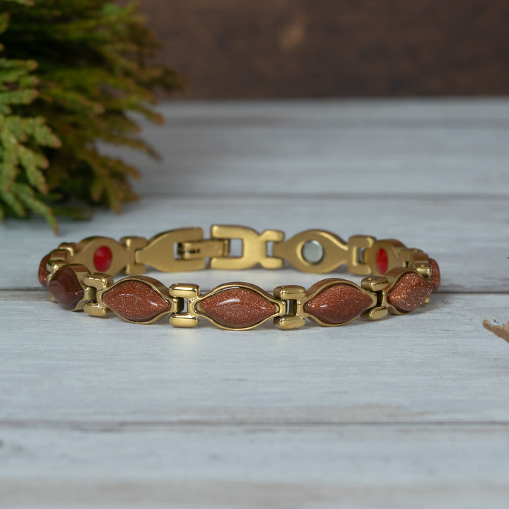 Magnetic Gold bracelet with red stones on a wooden surface