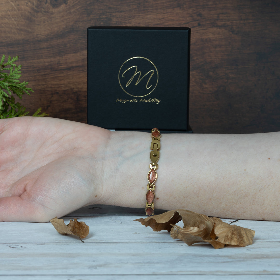 Bracelet on a wrist with a black box featuring a logo in the background