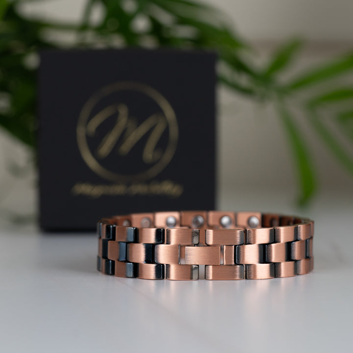 The Columbine Copper Bracelet in a clasped position, showing the smooth design of the clasp and sturdy link construction. The Magnetic Mobility gift box stands in the background.