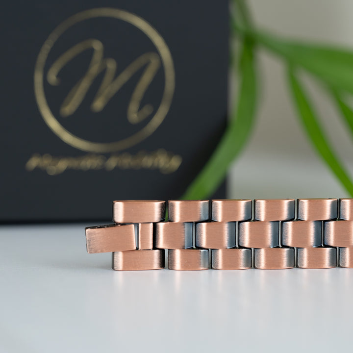 A detailed close-up of the bracelet's interlinked design, highlighting the dual-tone copper and silver finish. The precise craftsmanship of the Columbine Copper Bracelet is displayed.