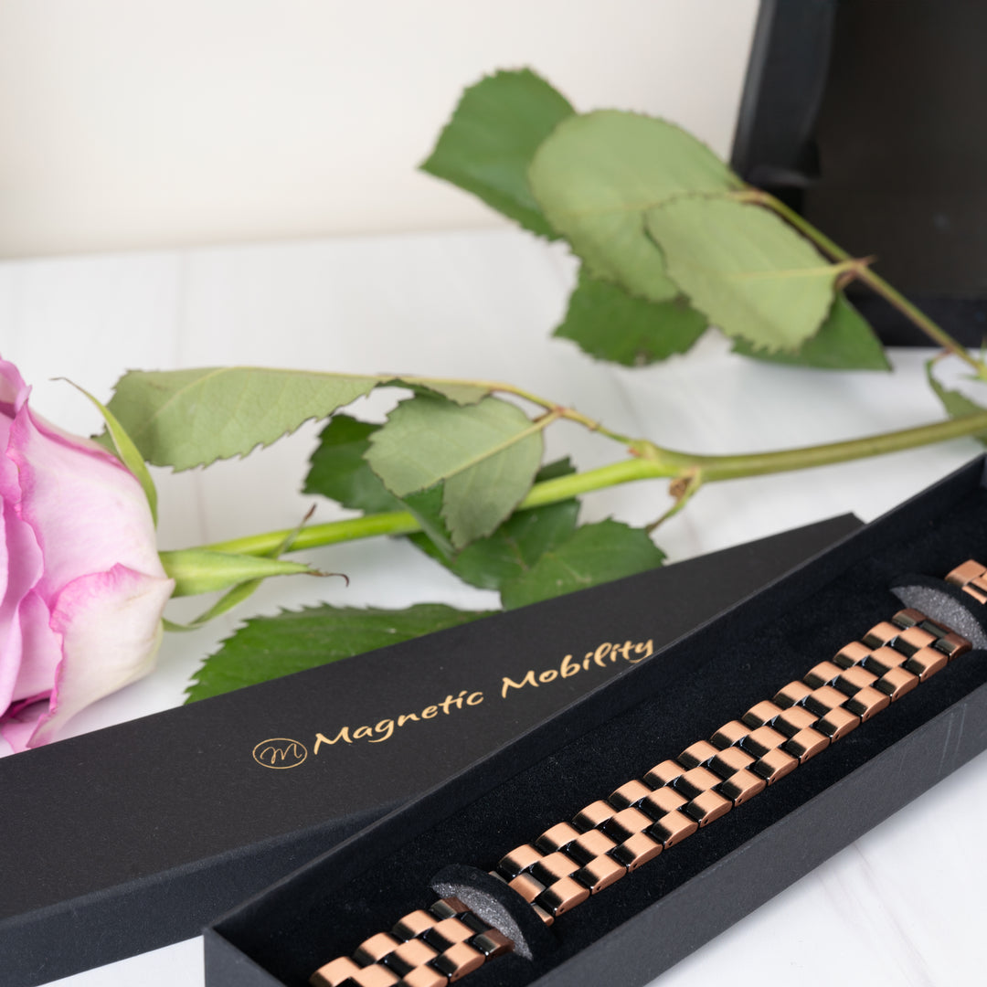 The Columbine Copper Bracelet displayed in a gift box, highlighting its intricate link style and copper sheen. The box features the Magnetic Mobility logo in gold.