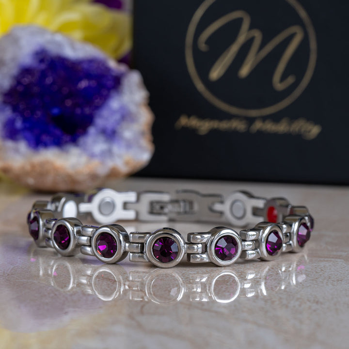 4in1 Magnetic bracelet with February birthstone Swarovski Amethyst crystals the background shows a black gift box with the Magnetic Mobility symbol and an amethyst geode