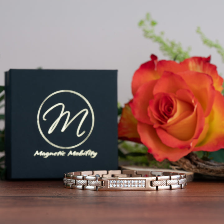 Honesty Dawn - 4in1 Magnetic bracelet with a centerpiece, adorned with two rows of shimmering Swarovski crystals. By Magnetic Mobility. Image shows the bracelet face on with a black box and a rose behind it