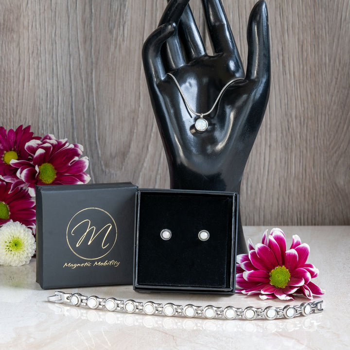 Comprehensive view of the June Birthstone gift set including a magnetic bracelet, necklace, and earrings with Swarovski Pearls, arranged stylishly on a marble surface with vibrant flowers. The set is perfect for June birthday gifts, combining elegance and wellness benefits.