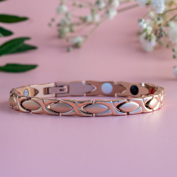 Laurel Dawn - a rose gold 4in1 Magnetic bracelet on a simple pink background with flowers. 