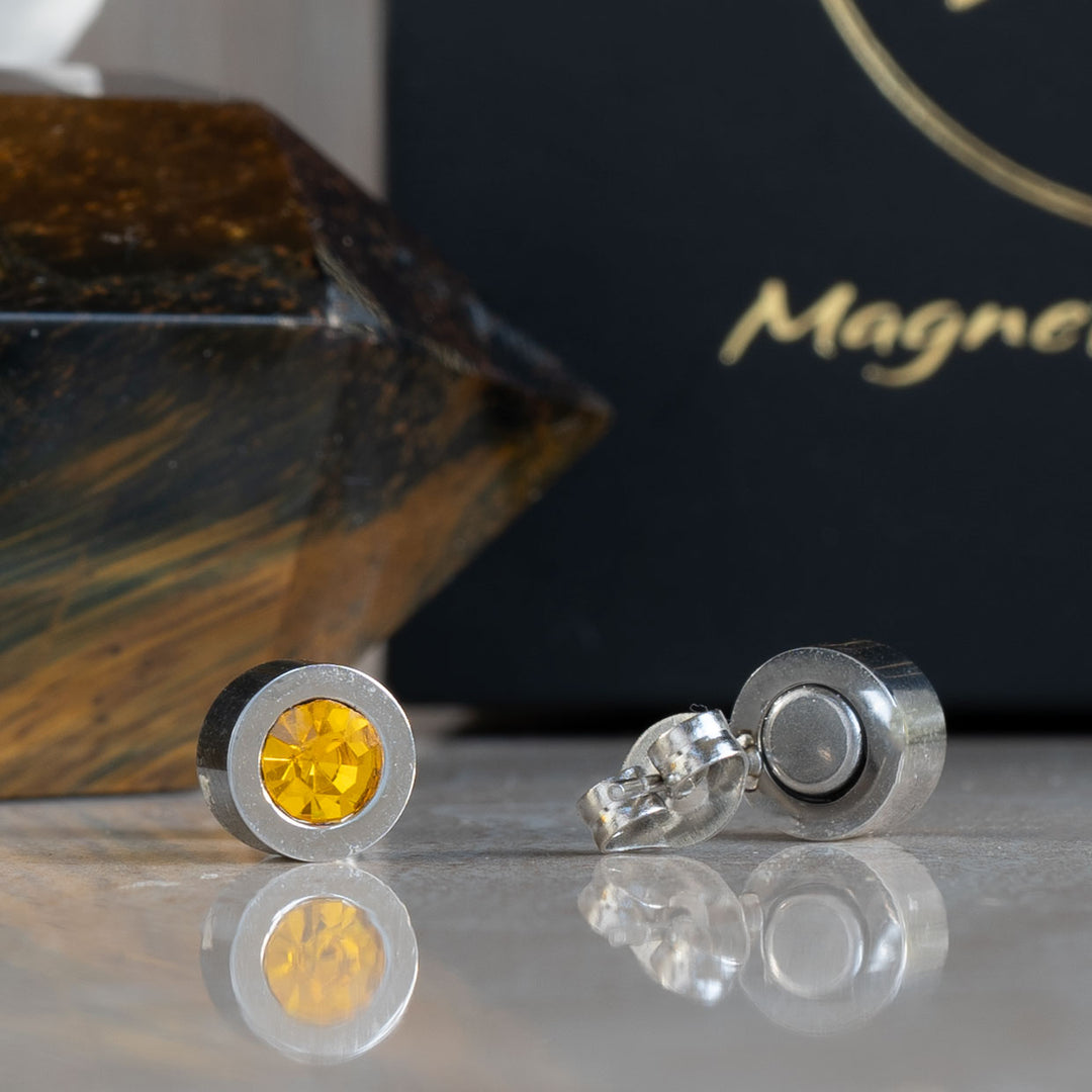 A detailed close-up of the back of the November birthstone earrings, showcasing the powerful magnets embedded in the earrings. The bright citrine stones contrast with the sleek metallic finish, emphasizing the dual purpose of beauty and therapeutic benefit.