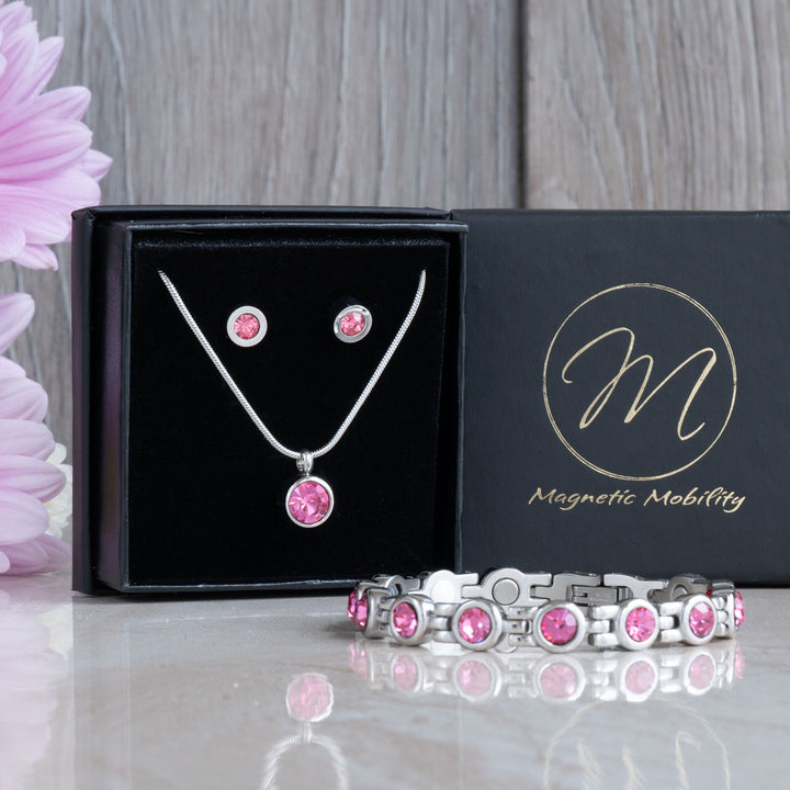 A complete October Birthstone Gift Set from Magnetic Mobility, featuring a pink tourmaline magnetic necklace, matching stud earrings, and a 4in1 magnetic bracelet. The set is beautifully presented in black, luxurious packaging with a pink flower accent.