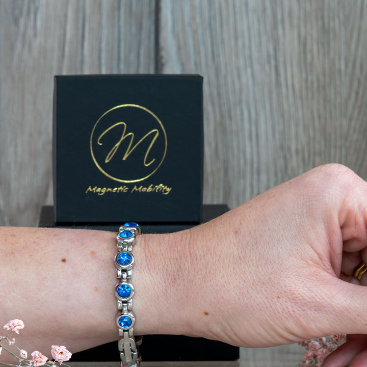 September Birthstone magnetic bracelet with stunning Swarovski Blue Sapphire crystals, shown on a wrist with a black gift box in the background. This bracelet blends vibrant beauty with therapeutic benefits, making it a perfect gift for September birthdays.