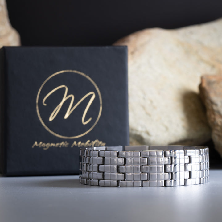 Magnetic Mobility's Thale Star 4in1 Bracelet designed for arthritis relief, displayed in front of a branded black box with a natural stone background