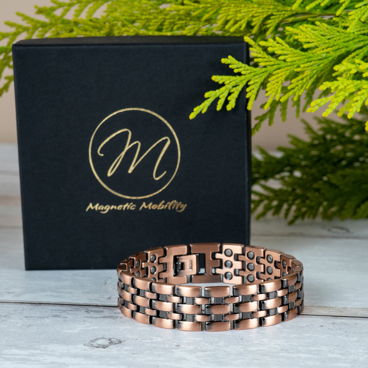 Wolfsbane copper magnetic link bracelet with dark recessed detailing beside a black Magnetic Mobility presentation box.