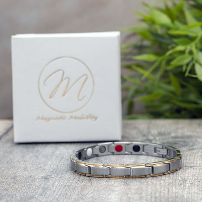 Apia Moon Magnetic Bracelet with silver colored stainless steel band and delicate gold lines on either side, featuring 4in1 elements on the back for arthritis pain relief. A stylish and functional piece of jewelry for everyday wear