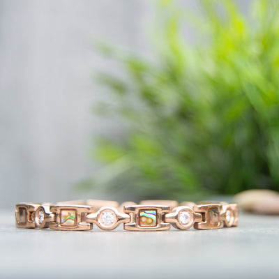 Avens Dawn Rose Gold MAgentic Bracelet with green plant in the background