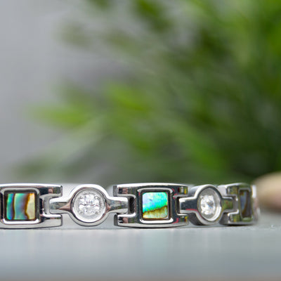 Close up view of Avens Moon Silver Magnetic Bracelet showing the irredessant desings in blue and green. White Crystals. 