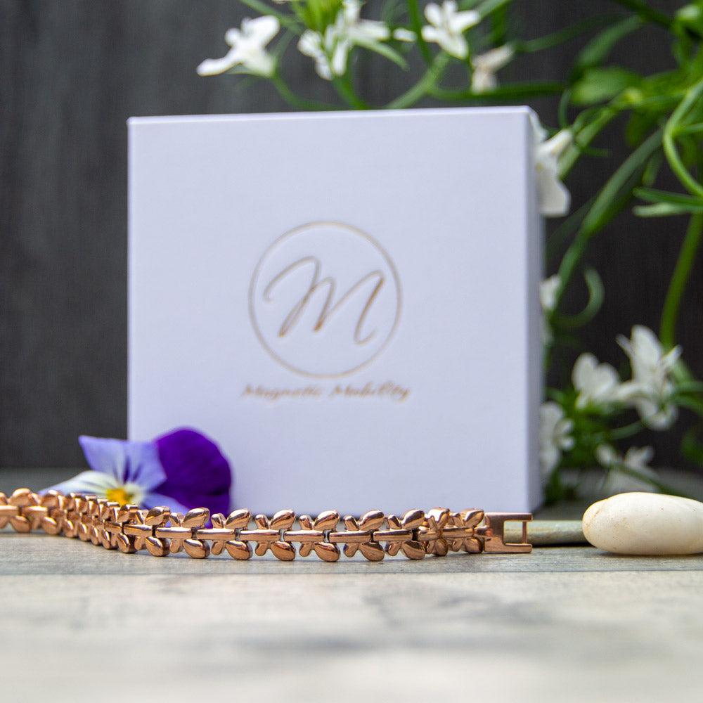 Buddleia Dawn - Rose Gold Coloured Women's Magnetic Health Bracelet with butterfly desings. Bracelet pictured in front of white Luxury gift box with flowers