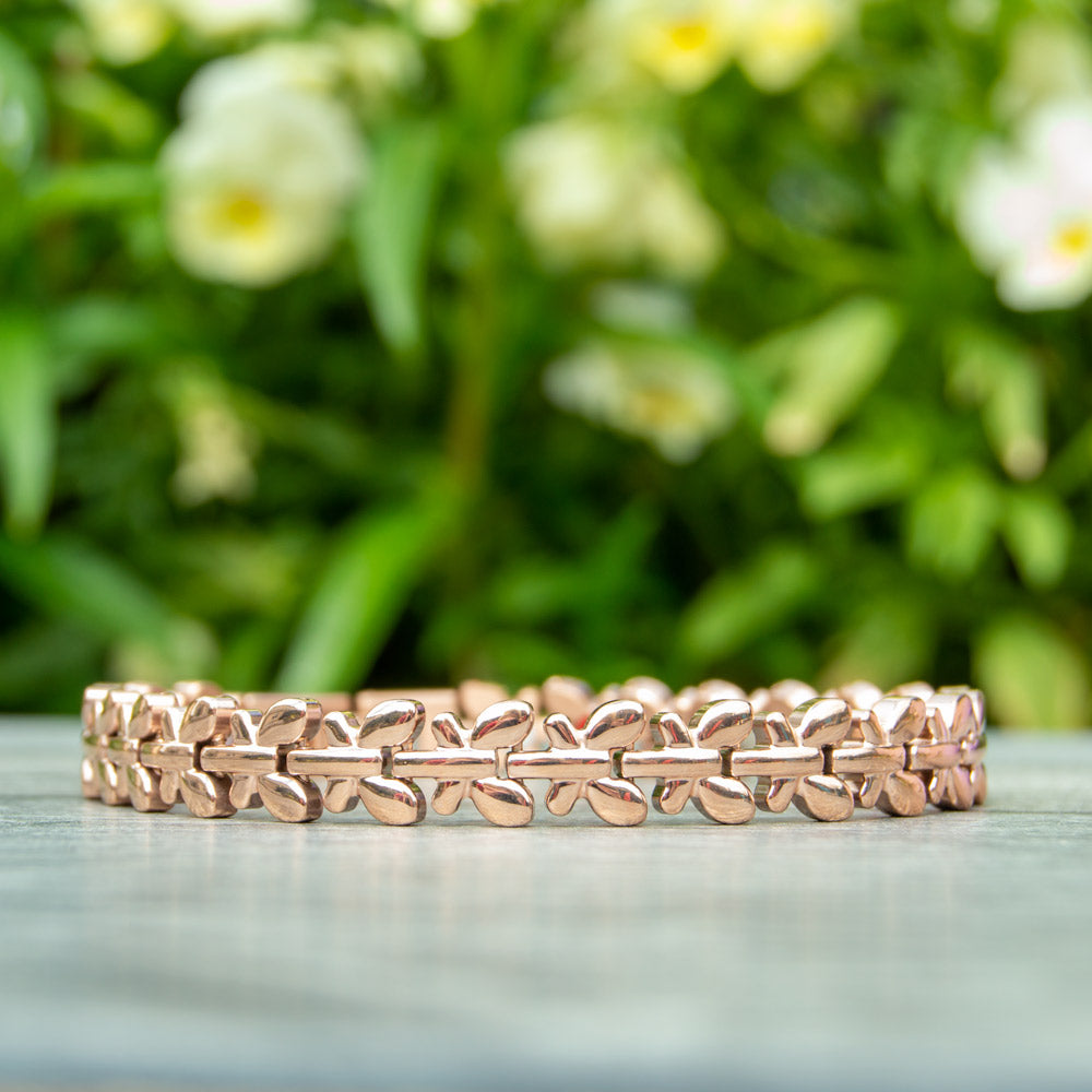 Buddleia Dawn - Rose Gold Coloured Magnetic Bracelet  front view - image shows the bracelet in front of Green plants