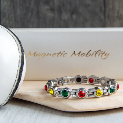 Carlow County GAA Inspired Women's Magnetic Bracelet laid on a hurl, symbolizing county pride and magnetic therapy benefits. Helps with migraines, sports injuries, fibromyalgia, and more. A fashionable addition to any outfit, perfect for GAA fans.