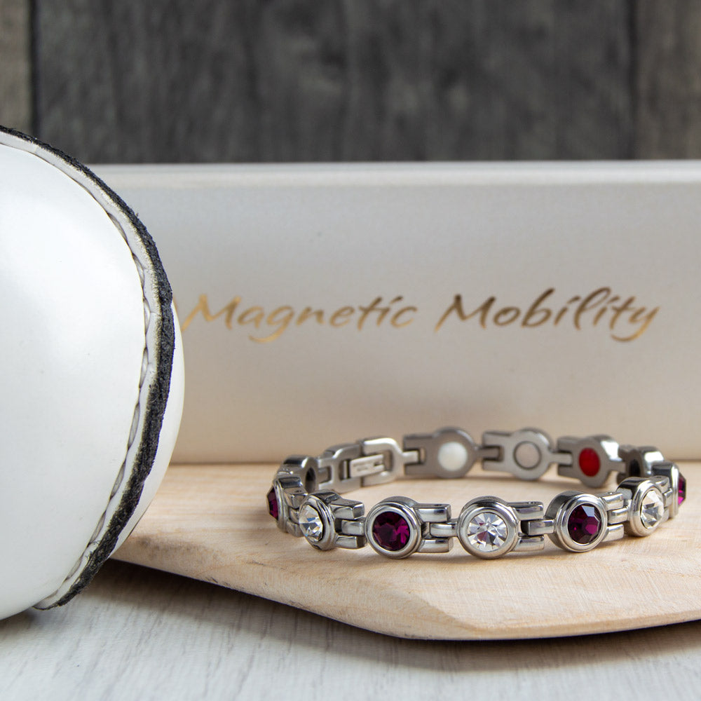 Galway County GAA Inspired Women's Magnetic Bracelet displayed on a hurl. Combining county colours with magnetic therapy benefits for conditions like migraines, sports injuries, and more
