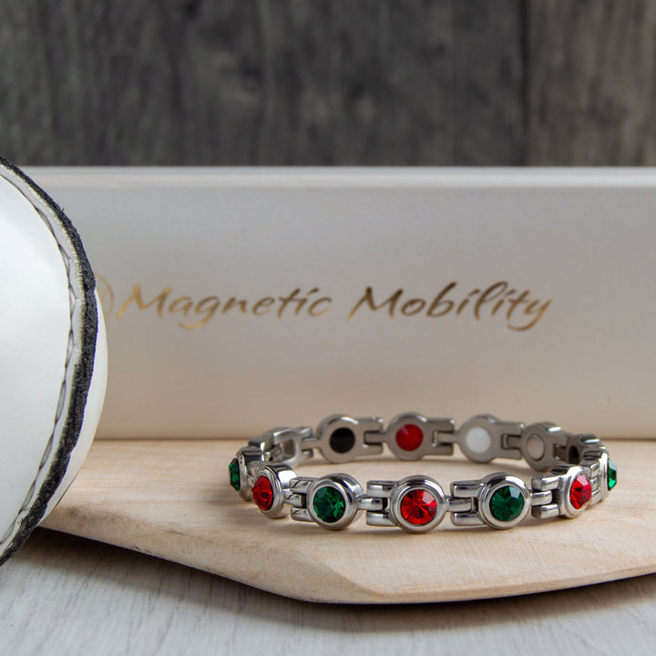 Mayo County GAA Inspired Women's Magnetic Bracelet placed on a hurl. Combining the pride of county colours with the benefits of magnetic therapy for conditions like migraines, sports injuries, and fibromyalgia.