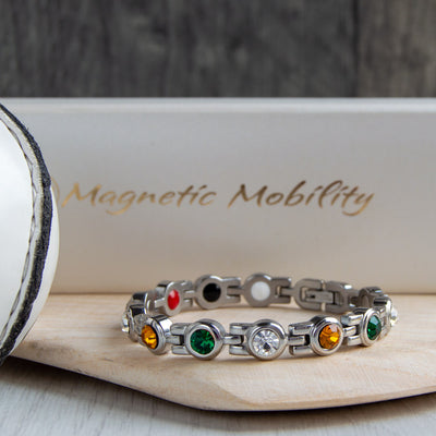 Offaly County GAA Inspired Women's Magnetic Bracelet showcased on a hurl. A symbol of county pride, providing magnetic therapy benefits for migraines, sports injuries, and fibromyalgia